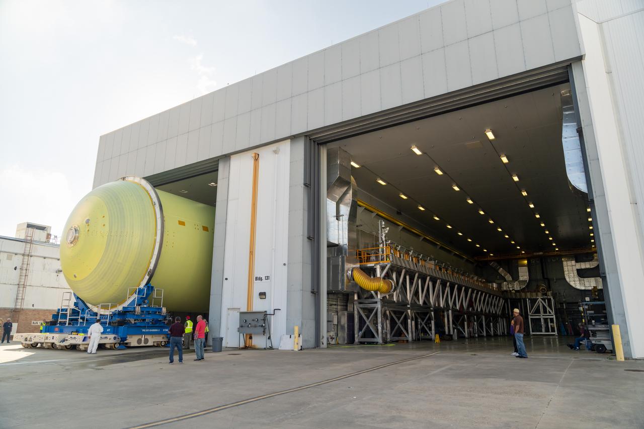 Teams move a liquid hydrogen tank for NASA’s SLS (Space Launch System) rocket out of a priming cell and into an adjacent cell on May 20 at the agency’s Michoud Assembly Facility in New Orleans. Inside the cell, the tank, which will be used on the core stage of NASA’s Artemis III mission, will receive its thermal protection system.  The thermal protection system, or spray-on foam insulation, provides protection to the core stage during launch. It is flexible enough to move with the rocket yet can withstand the aerodynamic pressures as the SLS accelerates from 0 to 17,500 mph and soars to more than 100 miles above the Earth. This third-generation insulation is more environmentally friendly and keeps the cryogenic propellant, which powers the rocket’s four RS-25 engines, extremely cold (the liquid hydrogen must remain at minus 423 degrees Fahrenheit/253 degrees Celsius) to remain in its liquid state. When applied the thermal protection system is a light-yellow color, which “tans” once exposed to the Sun’s ultraviolet rays, giving the SLS core stage its signature orange color.